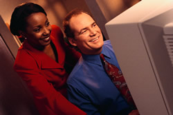 smiling businesswoman and businessman looking at computer monitor.